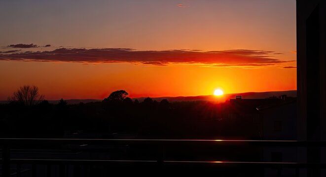 Sunset over horizon from urban balcony.