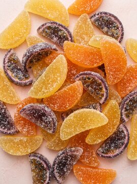 Top view of colorful assortment of sugar coated fruit flavored jelly candy slices on white background