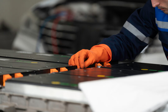 High-voltage battery checks, and maintenance. Technician or Mechanic wearing protective gloves diagnosing electric car vehicles battery, component checks at auto workshop