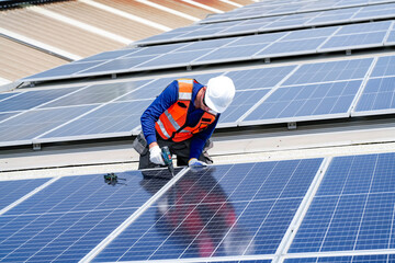 Worker installs solar panels on a roof during daytime in an industrial area © FotoArtist