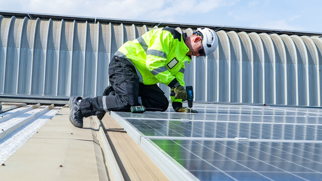 Worker installs solar panels on rooftop during daytime in a clear sky