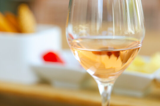 A glass of ros&eacute; wine catches the light beside small plates of appetizers in Greece, evoking Mediterranean leisure and refined summer dining.