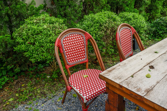 Luxury chair and wooden table set in english garden on a sunny day,outdoor seating for restaurant or cafe,Near paver patio with sitting area and small garden in forest.