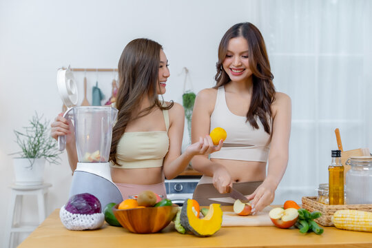 Two young women preparing fresh fruits and vegetables together in a bright modern kitchen promoting healthy eating active lifestyle nutrition friendship and everyday wellness.
