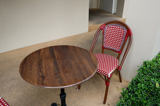 Luxury chair and wooden table set in english garden on a sunny day,outdoor seating for restaurant or cafe,Near paver patio with sitting area and small garden in forest.