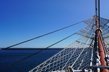 Bowsprit and rigging of a traditional sailing ship against blue sea and horizon © Yordan Balabanov