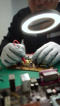 Close-up technician repairing a printed circuit board in a modern repair lab. PCB diagnostics, soldering electronic maintenance, right to repair. Sustainable technology and skilled technician.
