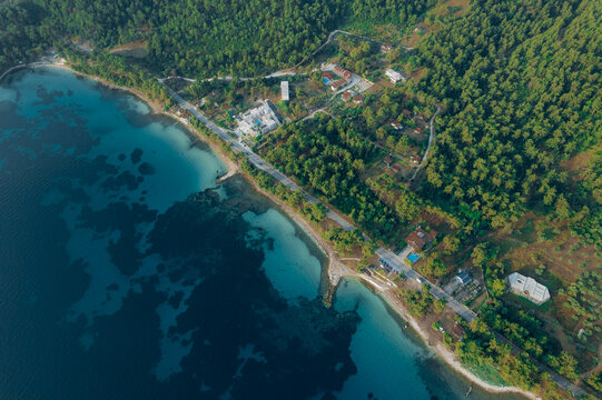 Aerial drone of a peaceful beach in Thassos, Greece, featuring transparent turquoise water, paddleboards, swimmers and a beautiful Mediterranean coastline.
