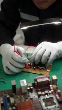 Close-up technician repairing a printed circuit board in a modern repair lab. PCB diagnostics, soldering electronic maintenance, right to repair. Sustainable technology and skilled technician.
