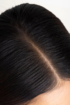 Close-up top view of woman scalp parting showing healthy hair roots and clean skin