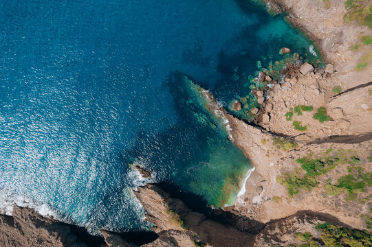 Aerial summer landscape of a turquoise lagoon on Thassos Island, Greece, showing crystal clear water, beach, swimmers, paddleboards and rocky coastline.