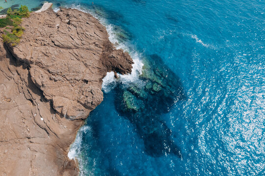 Aerial drone of a peaceful beach in Thassos, Greece, featuring transparent turquoise water, paddleboards, swimmers and a beautiful Mediterranean coastline.