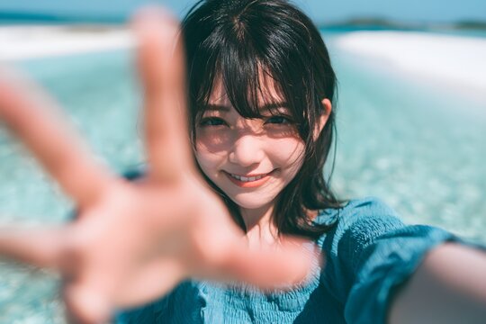 Young Japanese Woman Smiling and Reaching Out Hand in Tropical Ocean Waters on Sunny Day