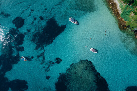 Aerial drone of a peaceful beach in Thassos, Greece, featuring transparent turquoise water, paddleboards, swimmers and a beautiful Mediterranean coastline.