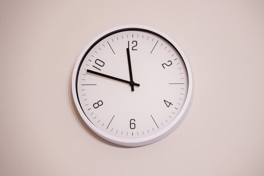 Minimalist wall clock on a white background representing daylight saving time, seasonal clock change in spring and autumn, time adjustment and schedule management with copy space.
