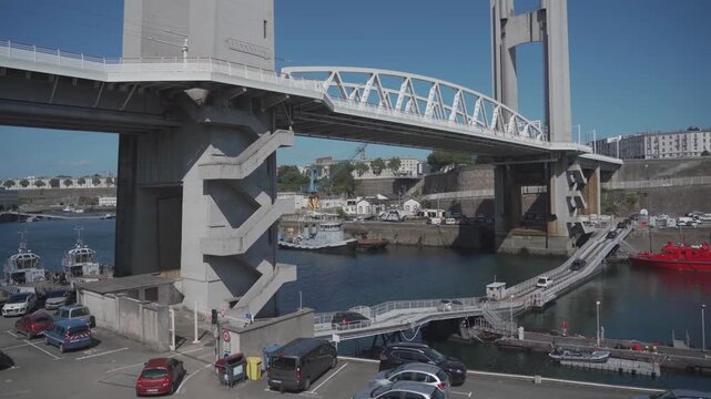 Port de Brest. Brest, a port city in France on the Atlantic coast. Industrial zone with cranes and docks, surrounded by a scenic bay. Bright, sunny day reflecting on ocean water and blue skies. 
