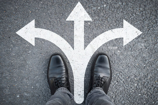 Conceptual image of person at three-way intersection choosing direction marked on ground with direction crossroads decision business strategy management planning thinking motivation