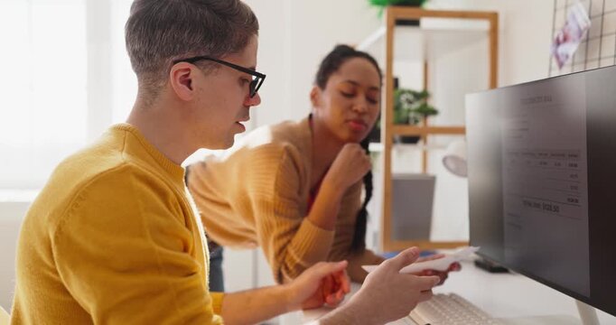 Couple organizes bills and budget at home. They use a computer to review payment and plan expenses online. Together they track costs and saving. Simple household budget and planning concept.