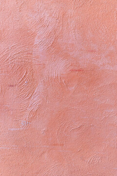 Textured salmon pink plaster wall with circular swirl patterns and rough stucco finish