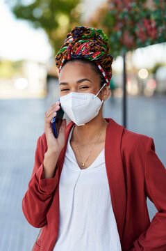 Woman wearing face mask talking on smartphone in urban setting