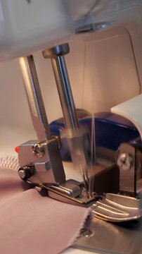 Detailed macro shot of an overlock sewing machine in operation, with its needles and loopers quickly creating a seam on a piece of fabric, symbolizing the textile industry and tailoring
