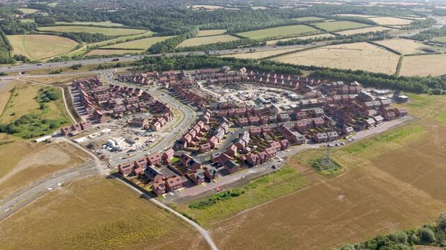 Aerial view above a new village being built on green belt land to fill the gap in the UK housing crisis with affordable new homes for first time buyers