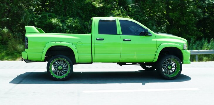 Wilmington, Delaware, U.S.A - Jul 2, 2026 - Lifted lime green 3rd generation Dodge Ram 2500 pickup truck with custom wheels and rear spoiler driving alongthe highway