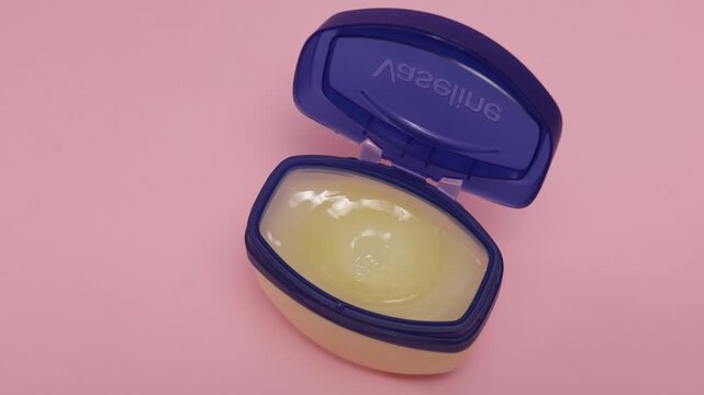 Petroleum jelly jar with blue lid open on pink background