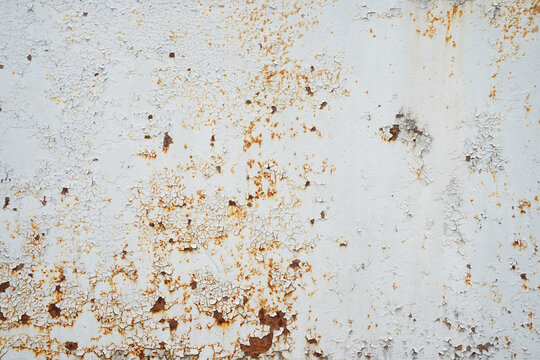Weathered white painted iron metal wall texture background with rust spots and peeling paint flakes. Vintage distressed steel surface, rusty metal panel for background design or layout overlay.