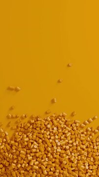 Close-up top view of rotating yellow polypropylene plastic granules and masterbatch resin pellet pile, 3D render seamless Vertical video.