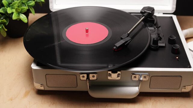 Vintage record player with spinning vinyl and red label on wooden table