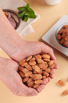 Fresh Raw Almonds in Cupped Hands - Healthy Natural Nut Snack on Wooden Background