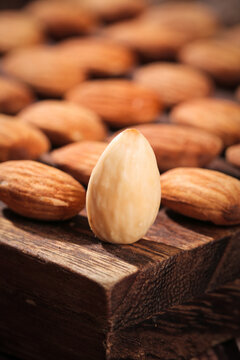 Single Blanched Almond on Wooden Surface with Nuts Background