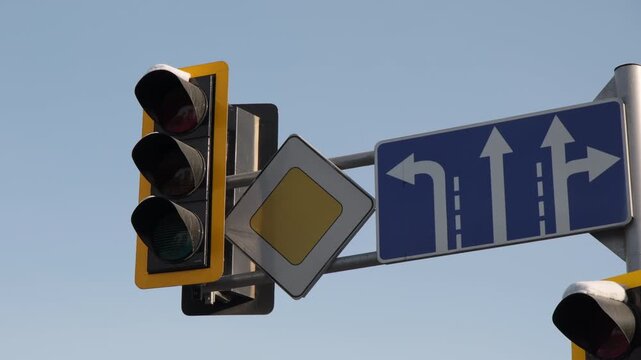 Road traffic light semaphores changing from green to red signal and signs on pole against background blue sky at city intersection