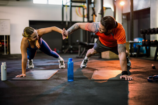 Fitness couple doing single-arm high five plank exercise in the gym