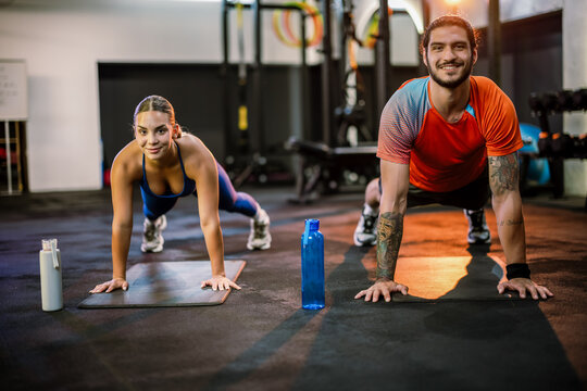 Athletic man and woman doing plank exercise together in the gym