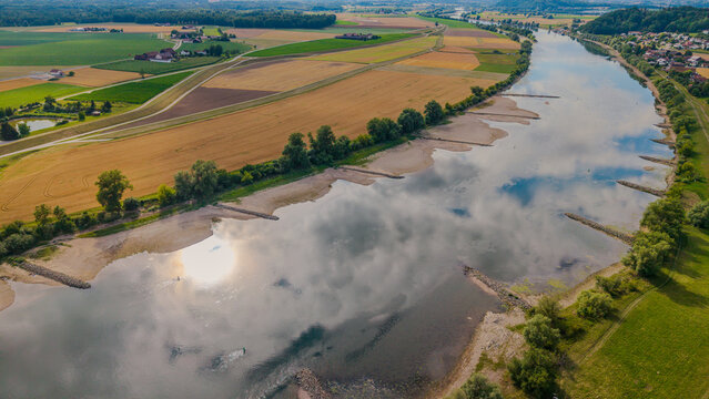 Ein Fluss flie&szlig;t durch eine Landschaft mit Feldern und B&auml;umen in der N&auml;he einer Siedlung