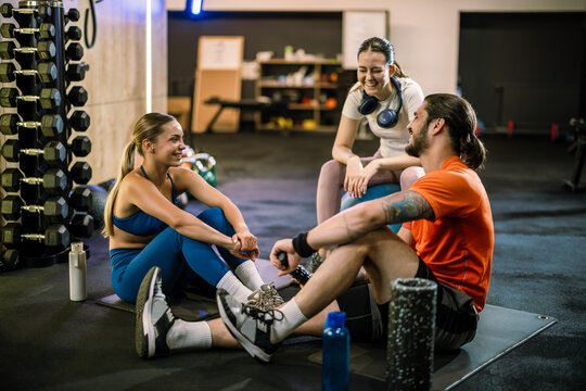 Athletic friends with yoga ball and foam roller resting in the gym