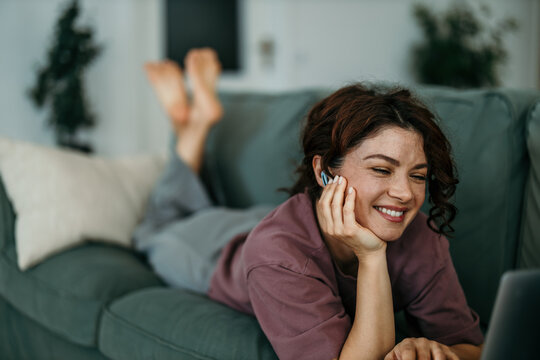 Woman laughing watching streaming content on laptop