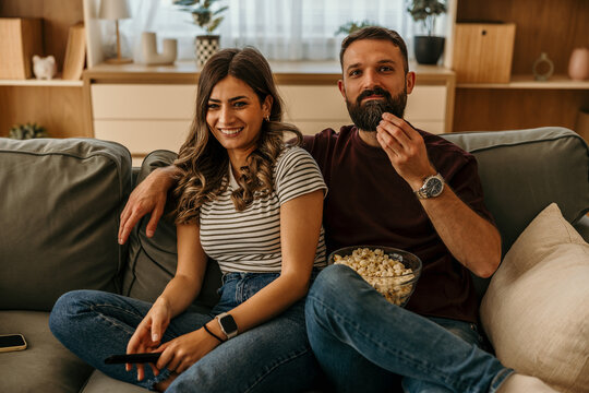 Couple enjoying movie night at home eating popcorn