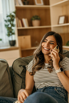 Woman talking on phone relaxing on sofa at home