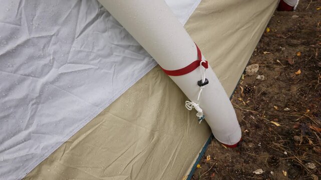Raindrops bead on the waterproof fabric seam and inflatable beam of a modern camping tent. Concept of high quality outdoor gear, camping durability, and weather protection.