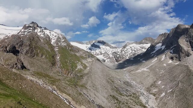 Cinematic panning aerial drone footage of a majestic alpine mountain range and glacial valley near Hochfeiler in the Zillertal Alps.