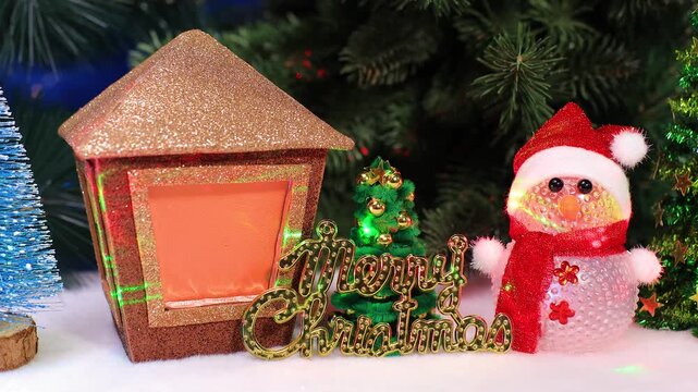 Against the background of Christmas trees, there is a small Christmas tree with letters between a snowman and a Christmas lantern