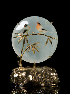 A high-end celadon jade sculpture with two vibrant songbirds perched on bamboo, a clear jade disc, a metallic gold cloud base, and oriental home decor