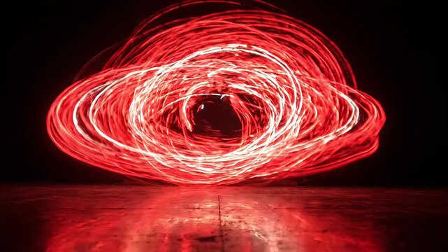 Red light painting vortex on dark reflective ground.