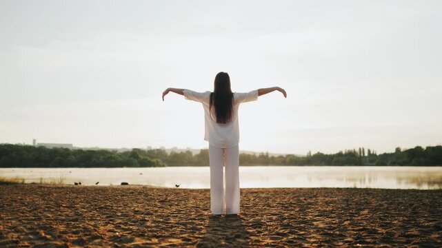 Adult female raising arms at the beach embracing ultimate freedom.