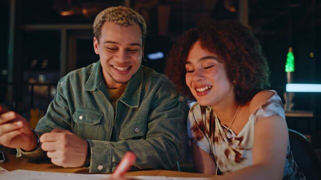 Young couple sketching wireframe design with markers together in night studio