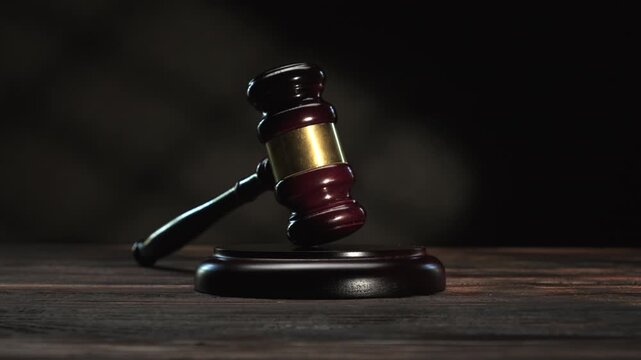 Ceremonial gavel on stand on wooden table against dark background close-up