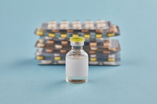 A transparent bottle with pills and medicine for injection on a blue background. The concept of alternative treatment.